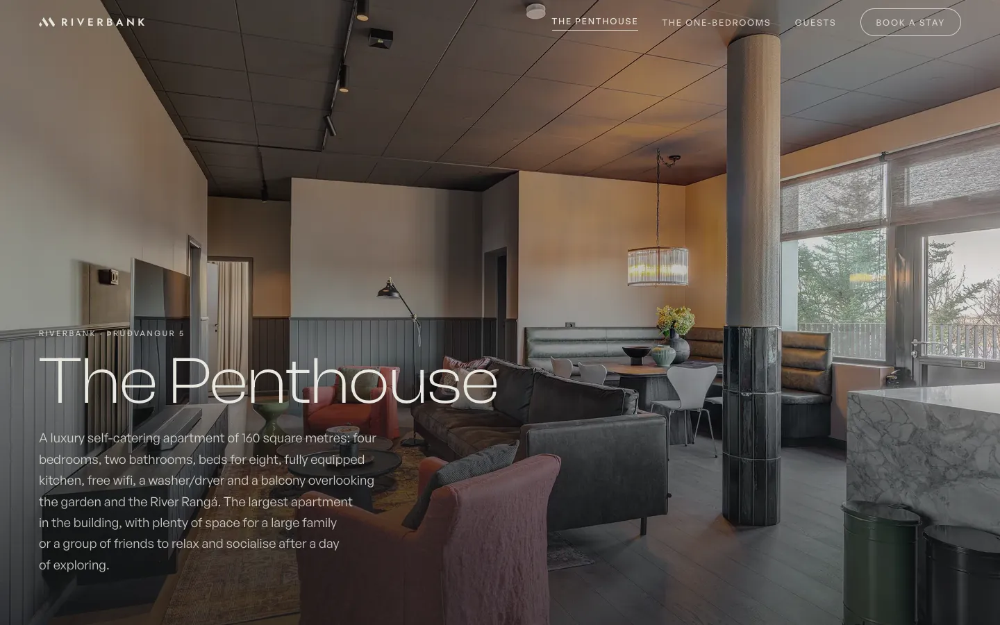 Síða þakíbúðarinnar á riverbank.is: stofan með stórum gluggum, undir fyrirsögninni The Penthouse